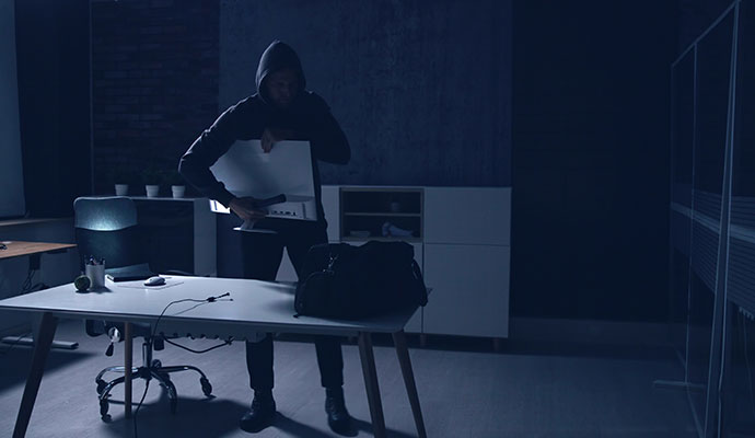 A burglar stealing a computer monitor from a office desk
