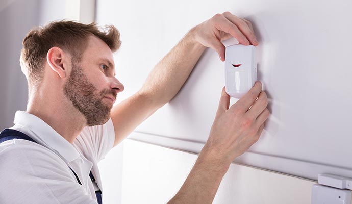 An expert installing motion sensor on the wall