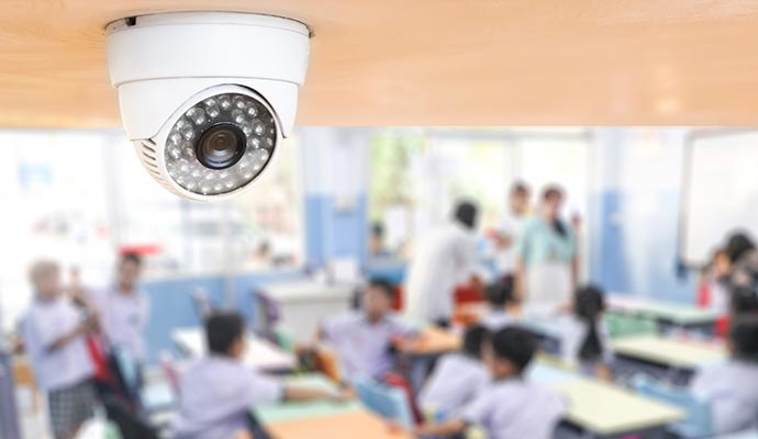 A security camera mounted on the ceiling of a classroom