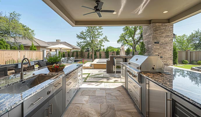 Covered outdoor kitchen with stainless steel grill and granite countertops
