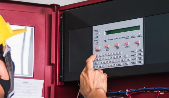 A person controls a fire alarm panel