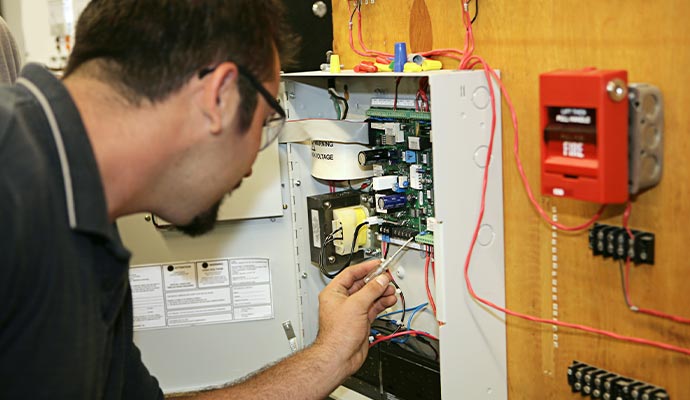 Professional worker repairing fire alarm system