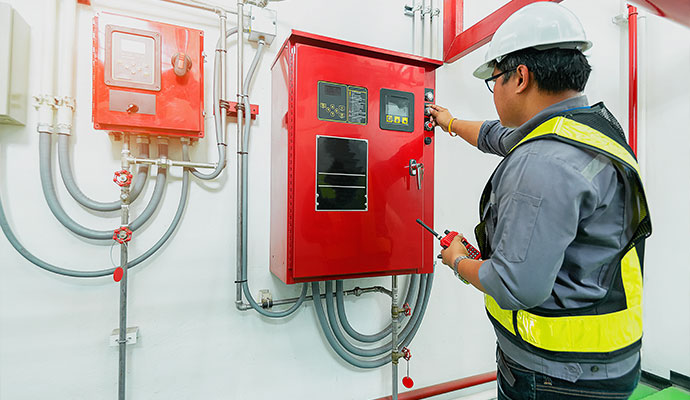 Technician inspecting industrial fire alarm controls