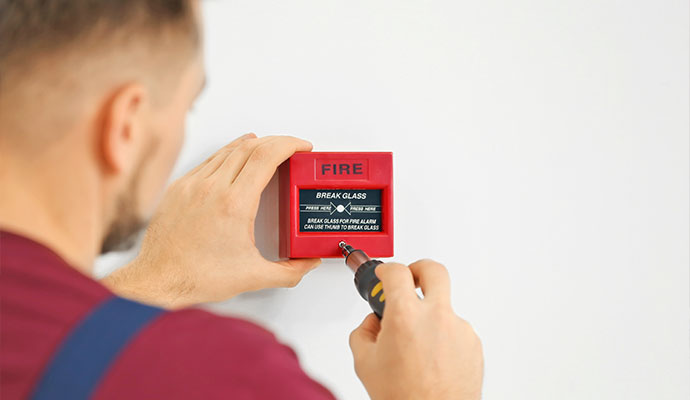 Technician installing a break glass fire alarm