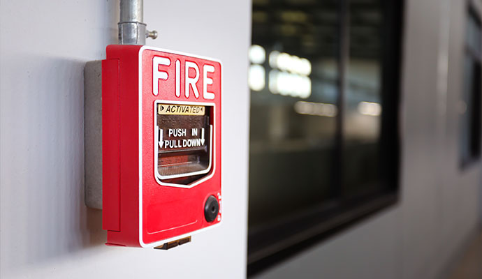 A close-up shot of a red manual fire alarm pull station mounted on a wall