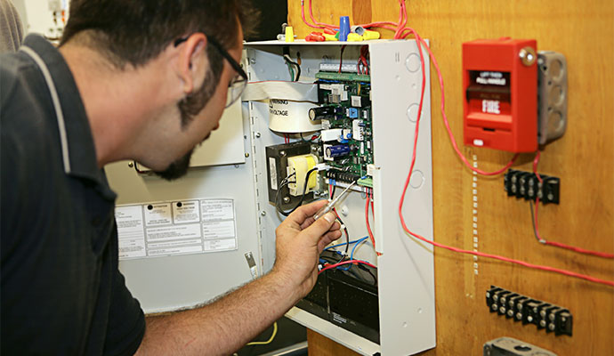 Technician inspecting a fire alarm control panel