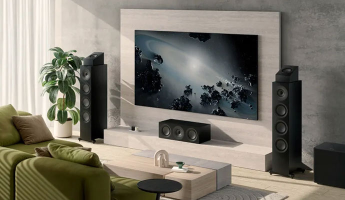 A premium home cinema setup featuring black KEF R Series floorstanding speakers