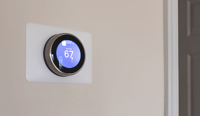 A sleek, circular digital smart thermostat mounted on an interior wall