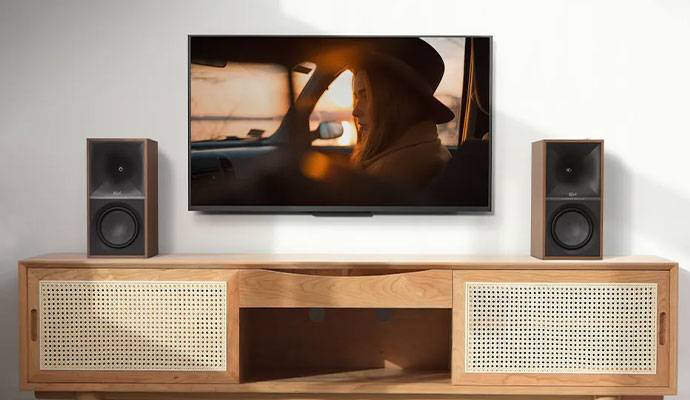 A pair of walnut KEF Wireless II speakers flanking a wall-mounted TV