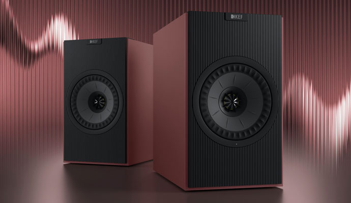 A pair of premium KEF wireless bookshelf speakers in a matte red-orange finish