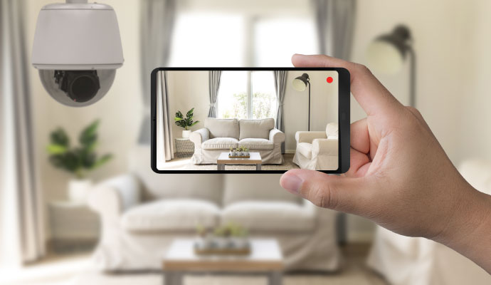 Person viewing live home security camera footage on a smartphone in a living room