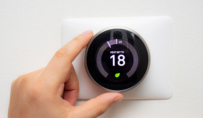 Hand adjusting temperature on digital wall-mounted smart thermostat
