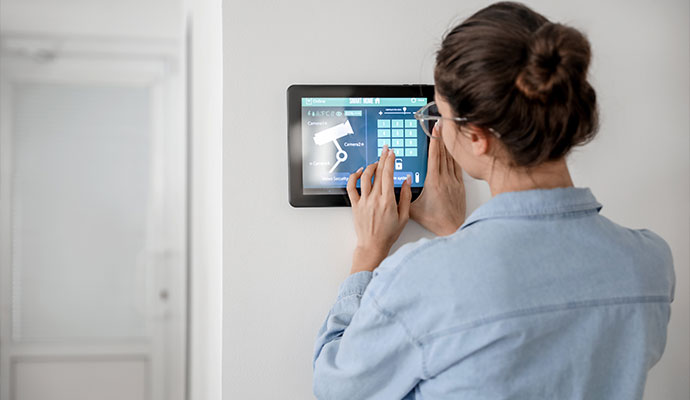 Homeowner adjusting settings on wall-mounted interactive security panel