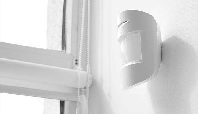 White motion sensor mounted on interior wall near window