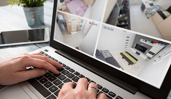 Laptop displaying live indoor home security camera video feeds