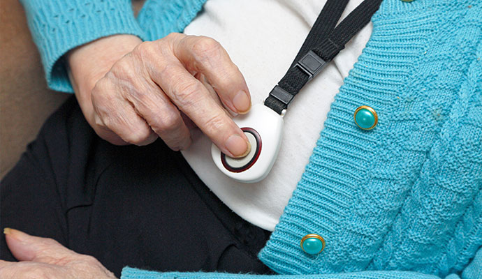Senior pressing emergency button on wearable medical alert pendant
