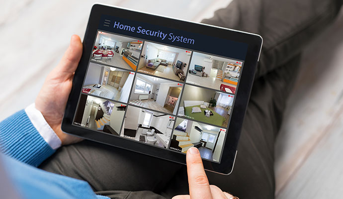 Person holding tablet displaying 24/7 live home security camera feeds