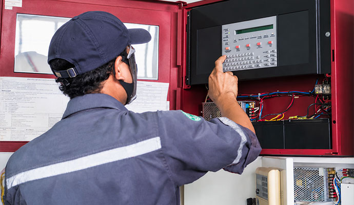 Technician testing and inspecting a fire alarm monitoring control panel