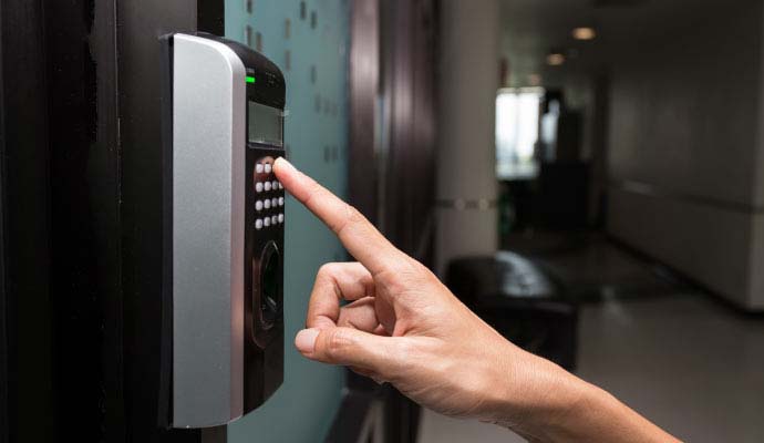 Person entering PIN code on door keypad access control reader