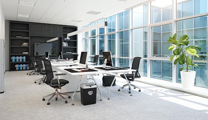 Modern commercial office space with organized desks, bright windows and professional workplace environment