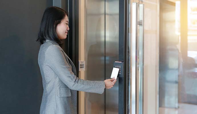 Office employee swiping keycard to open glass entry door