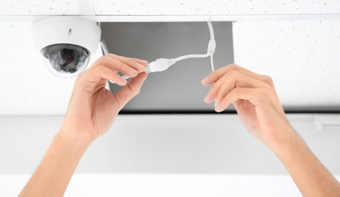 Technician connecting cables while installing a ceiling-mounted security camera