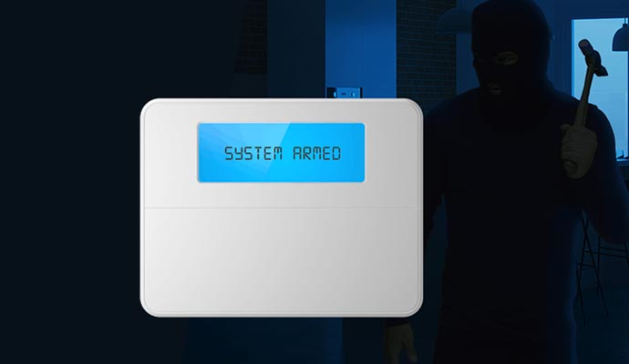 A home security control panel displaying SYSTEM ARMED in a room.